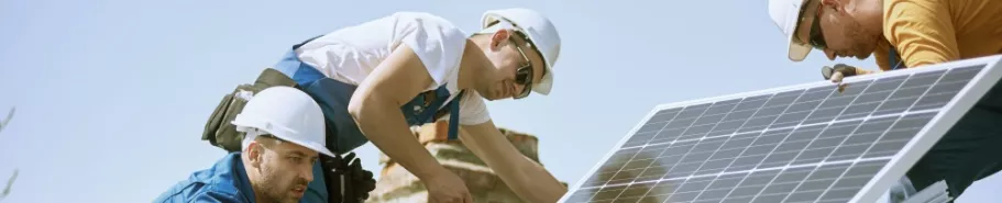 Pracownicy zakładają panele fotowoltaiczne na dachu